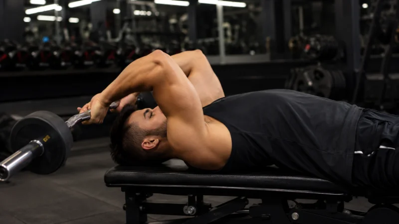 Athlete performing lying barbell triceps extension to target long head tricep exercises