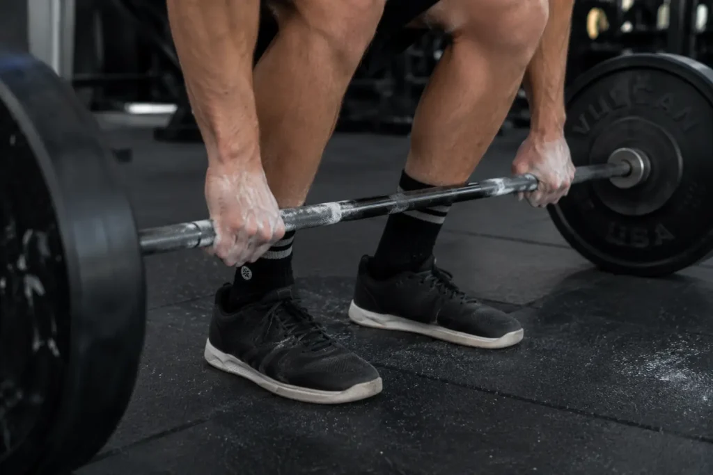 Close-up of hand and shin position showing proper deadlift form during the pull