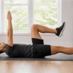 Person performing the dead bug exercise on a mat with arms and legs raised for core stability